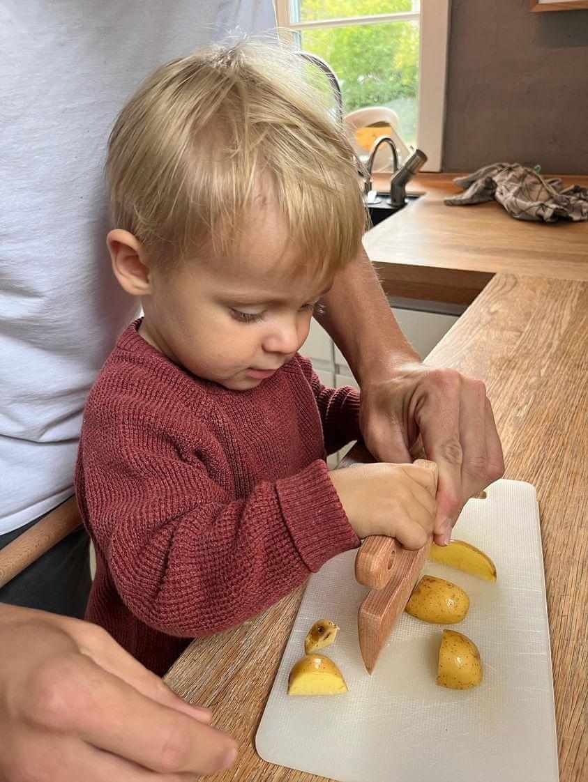 Barn skär frukt med barnkniv i trä