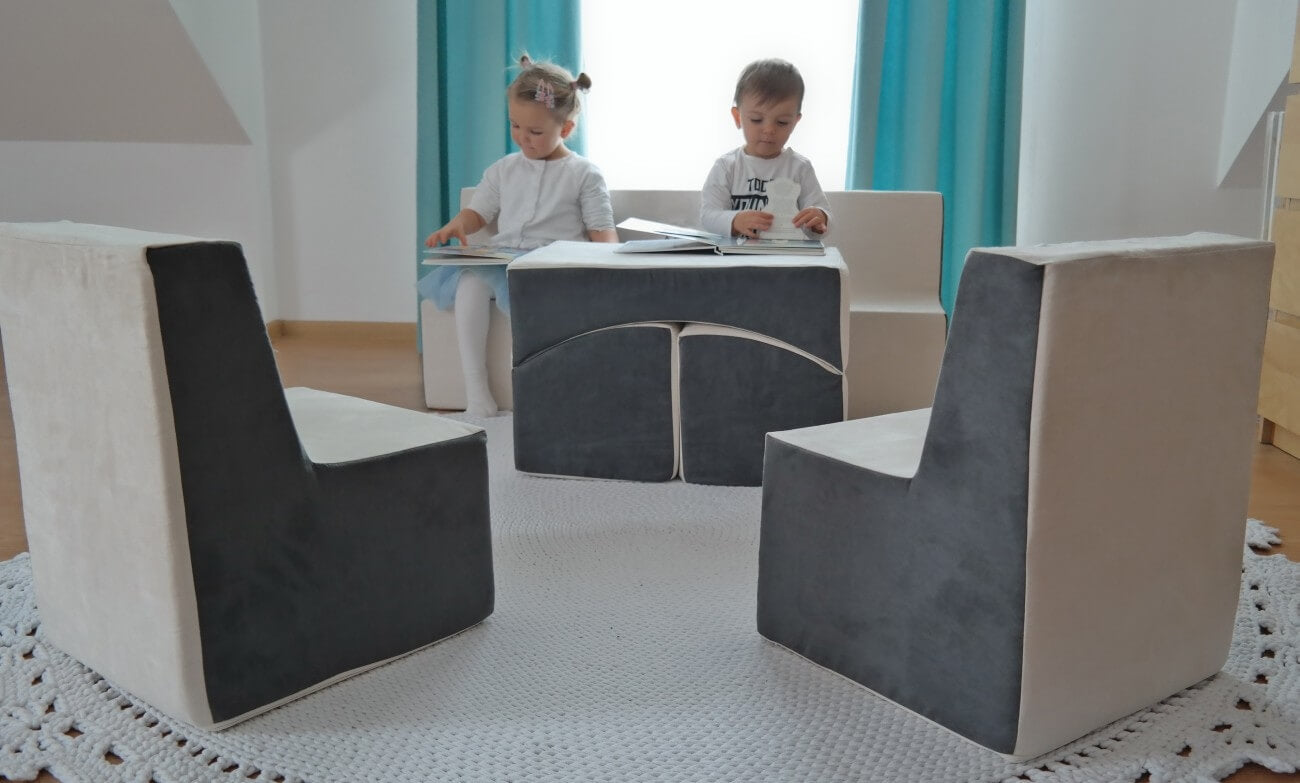 To børns sidder i sofaen af legeskum og kigger på billedbøger