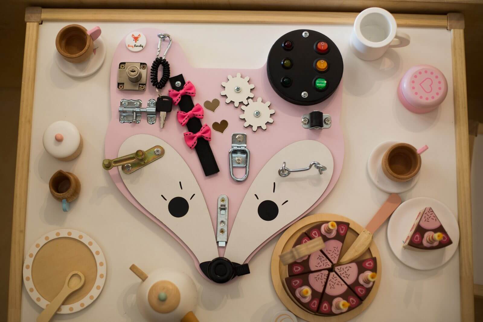 aktivitetstavle ligger på legebord med kager, tallerkner og bestik